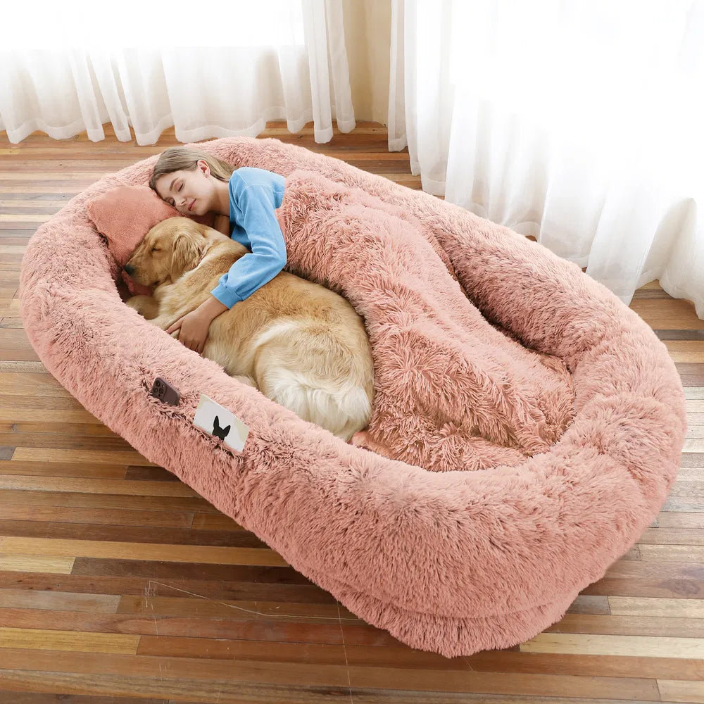 Woman and golden retriever on a pink giant faux fur bed