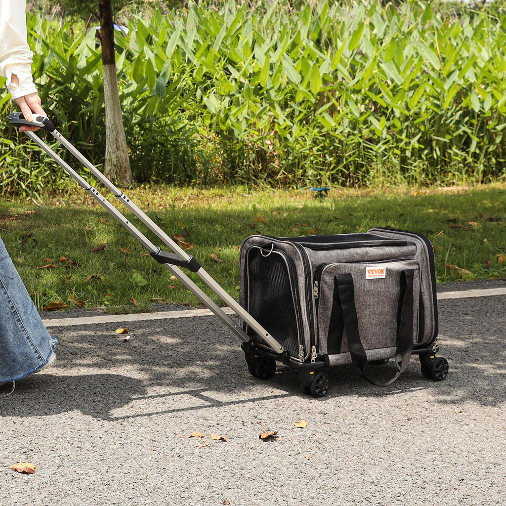 Owner wheeling the grey pet carrier by its telescopic handle along a park path