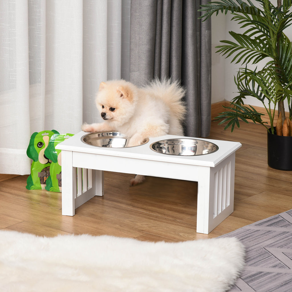Fluffy Pomeranian at a white wooden raised dog feeder in a living room