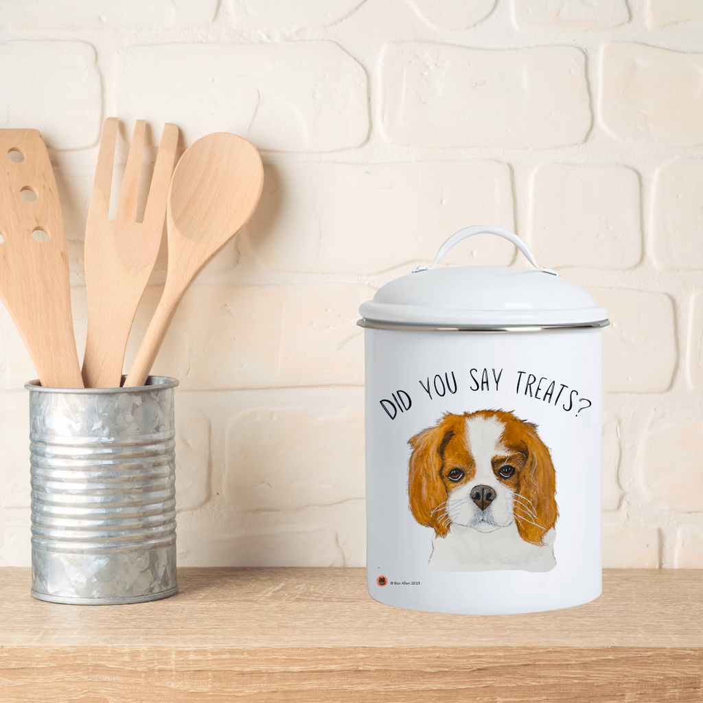 Cavalier treat jar on a wooden worktop beside a pot of wooden spoons and a white brick wall
