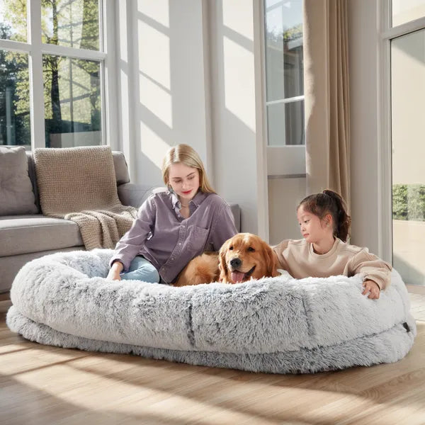 Woman, child and golden retriever relaxing on a grey giant dog bed