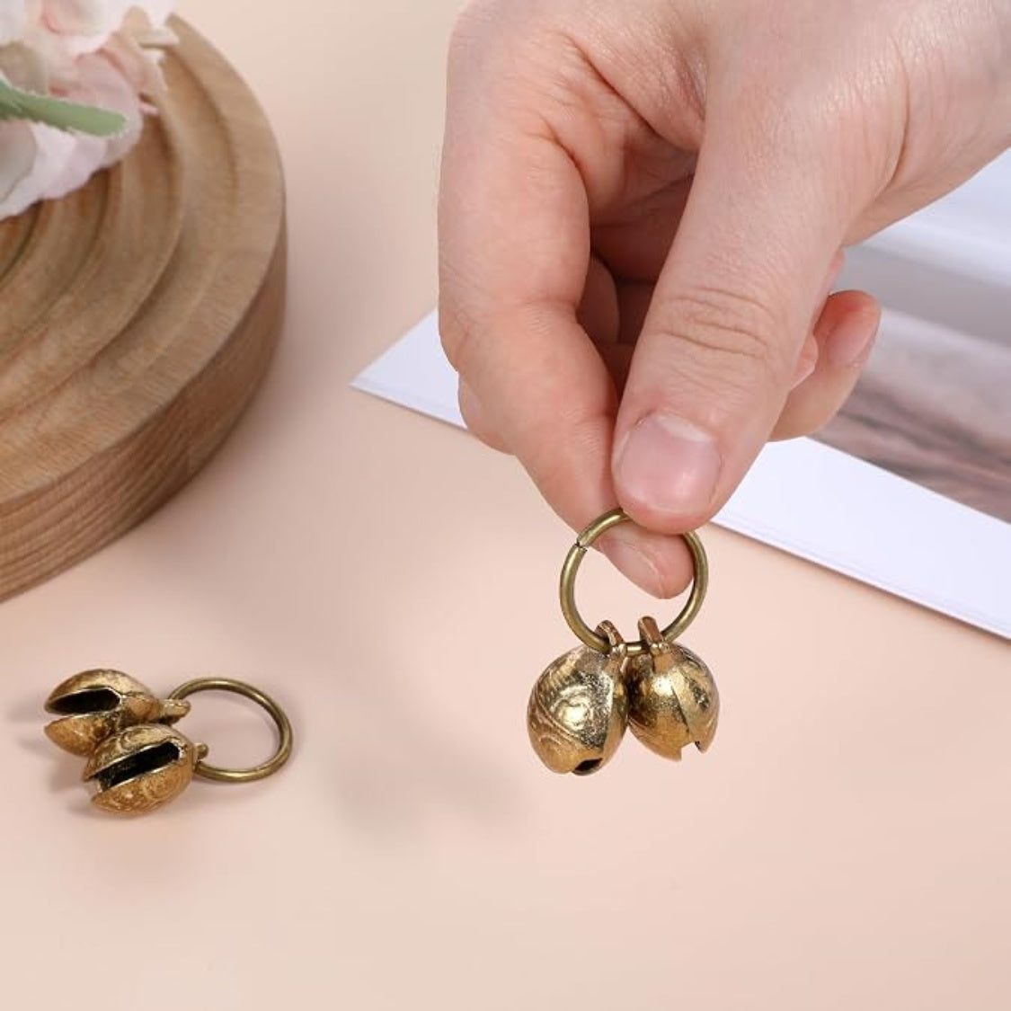 Hand holding a pair of brass collar bells on a ring