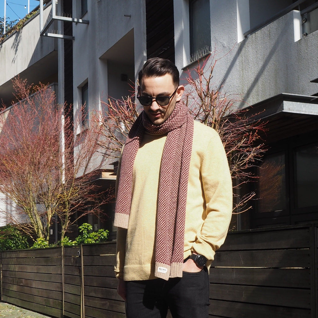 Man in sunglasses wearing a long burgundy check wool scarf on a city street