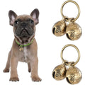 French bulldog puppy wearing a brass bell on a green collar, beside two pairs of bells