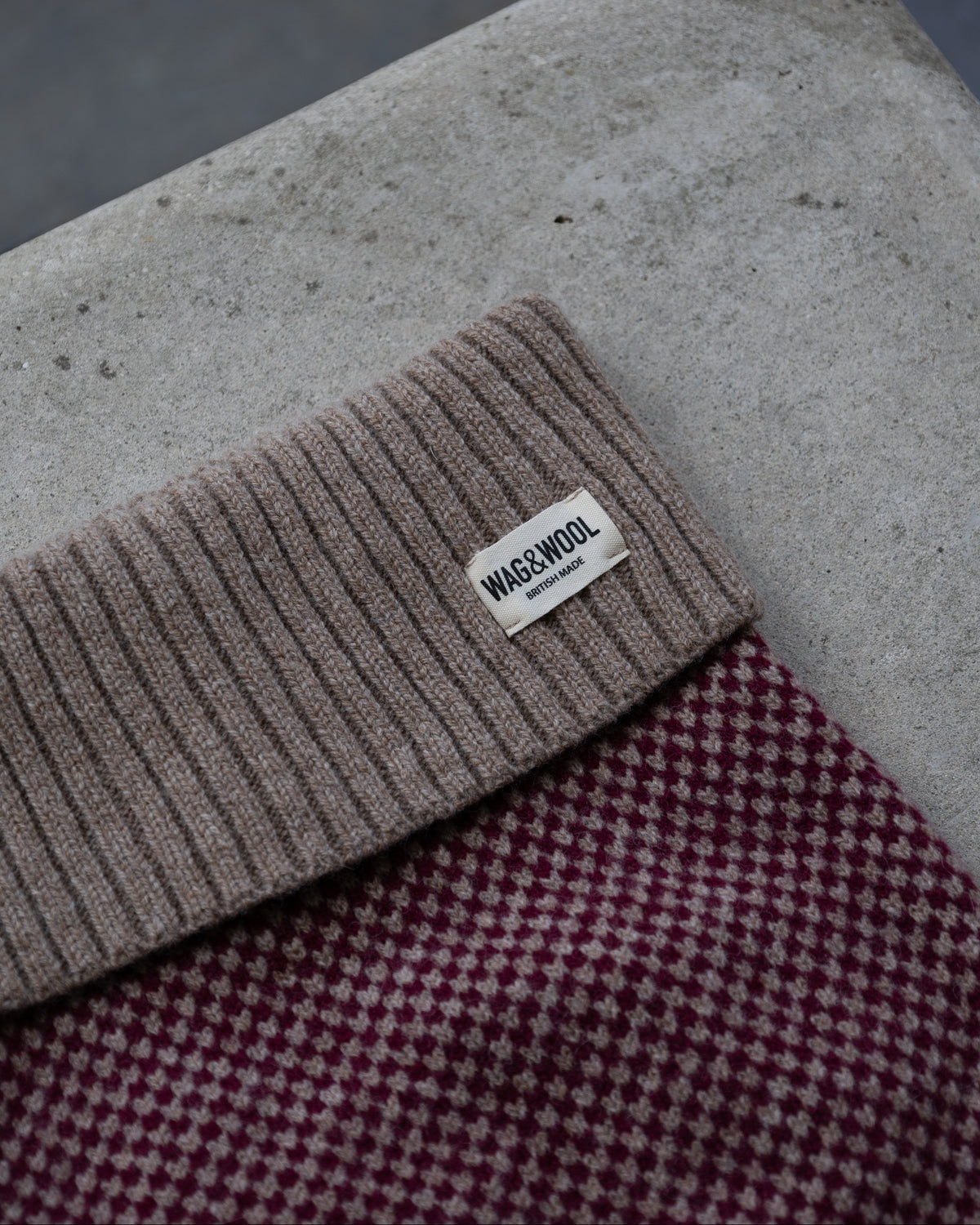 Close-up of the taupe roll neck and label on the burgundy check jumper