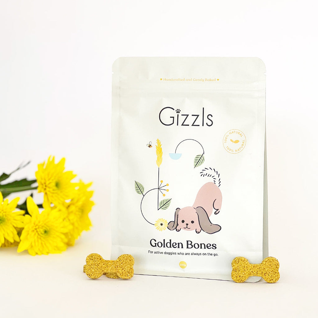 Gizzls Golden Bones 200g pouch with two golden bone biscuits and yellow flowers