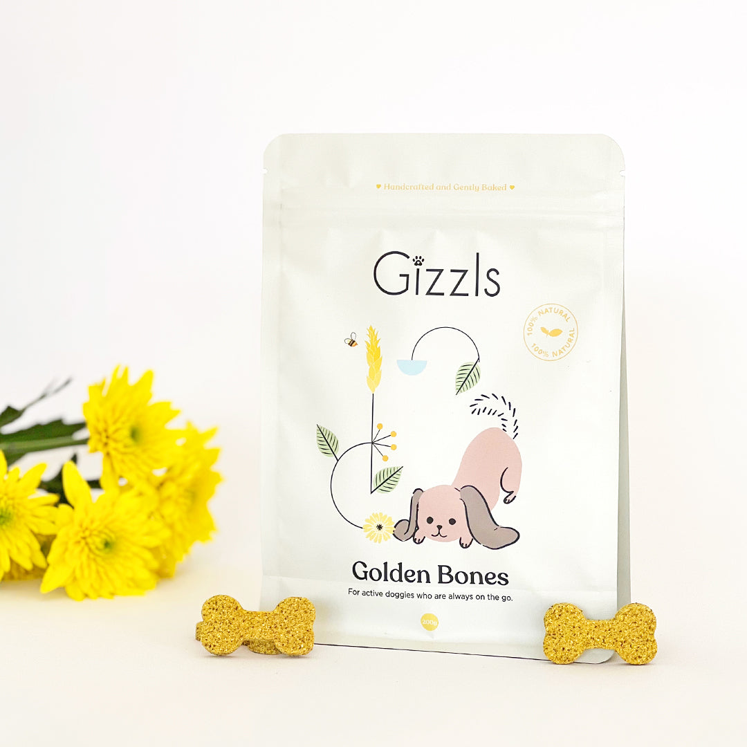 Gizzls Golden Bones 200g pouch with two golden bone biscuits and yellow flowers