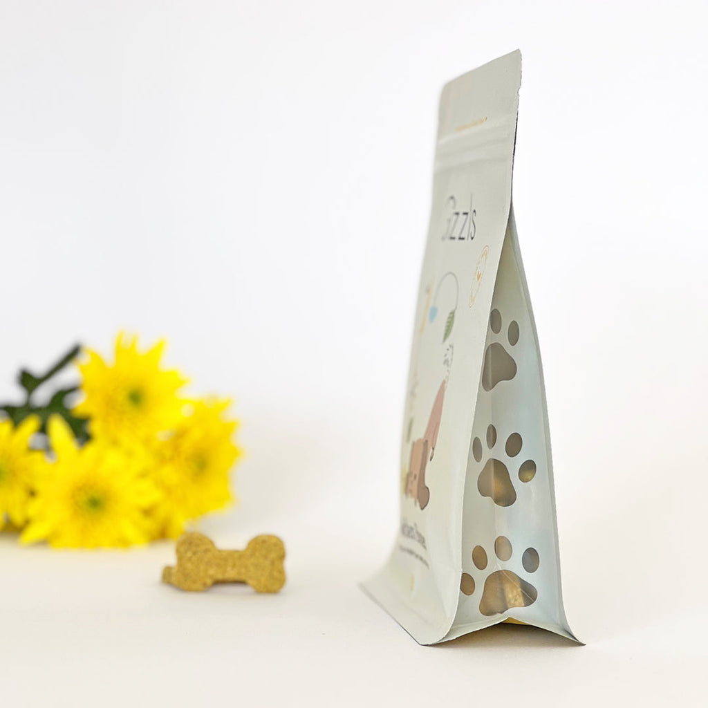 Side view of Gizzls Golden Bones pouch with paw-print window and a bone biscuit