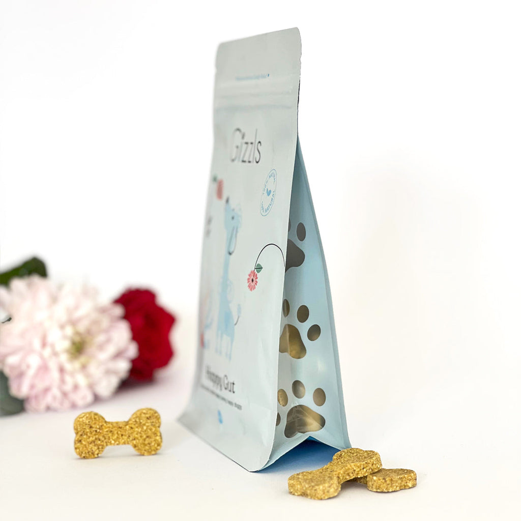 Side view of Gizzls Happy Gut pouch with paw-print window and bone biscuits