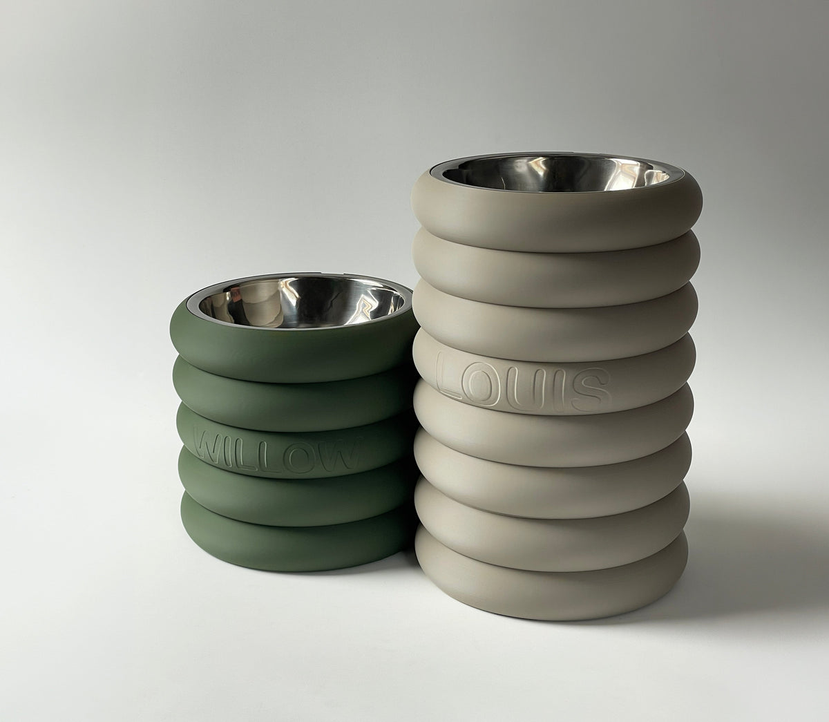 Tall Rings raised dog bowl stand in stone beside a shorter green stand, steel bowls