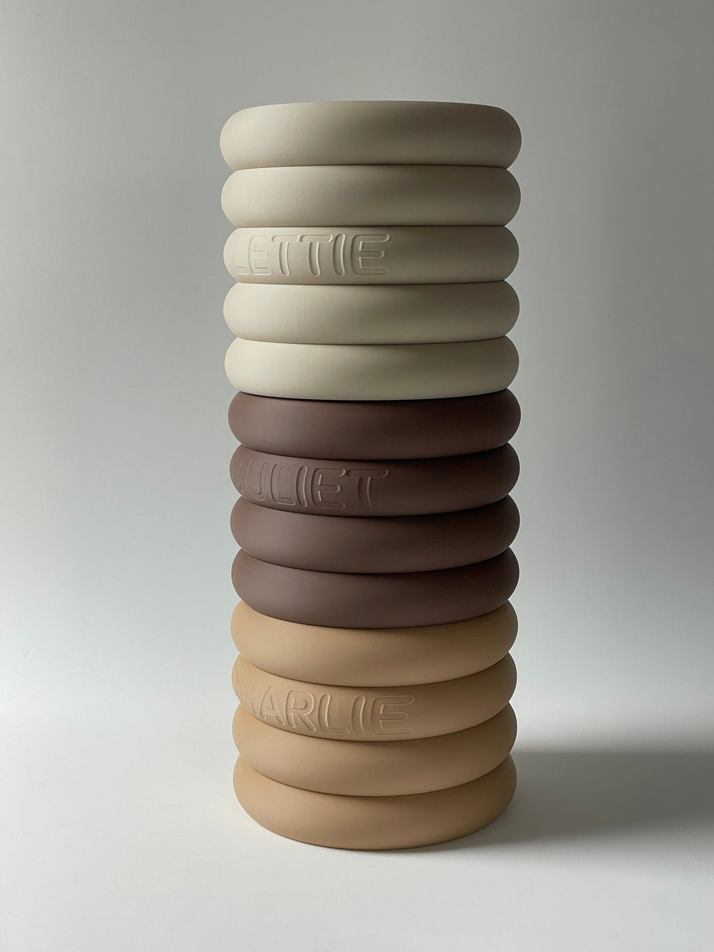 Stack of ring stands in cream, brown and sand showing the tiered ring design