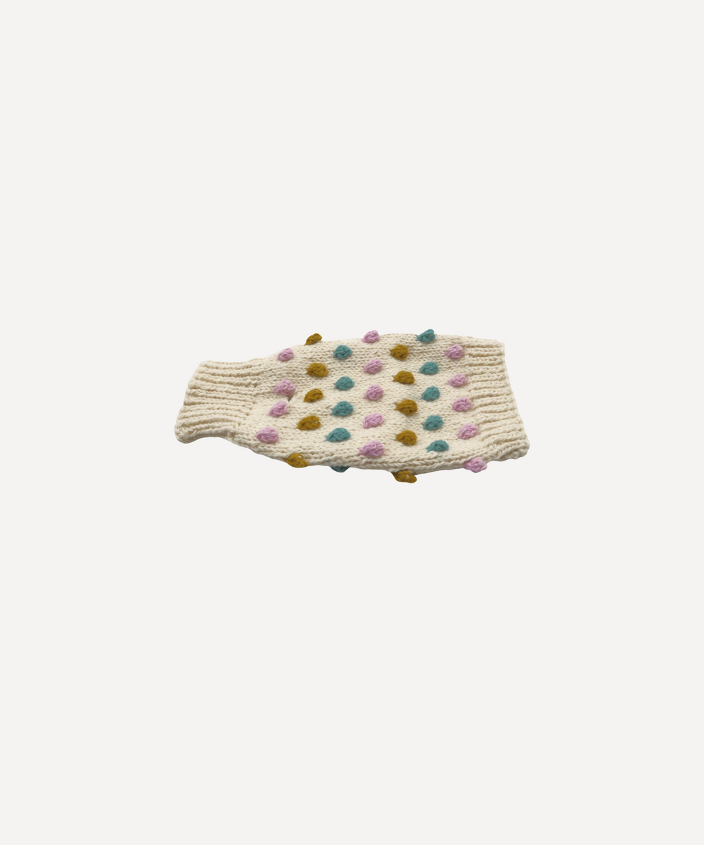 Cream hand-knitted dog jumper with colourful pom-pom bobbles, laid flat