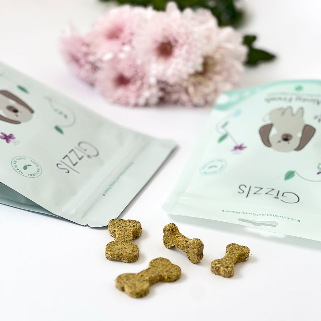 Minty Fresh pouches lying flat with bone biscuits and pink chrysanthemums