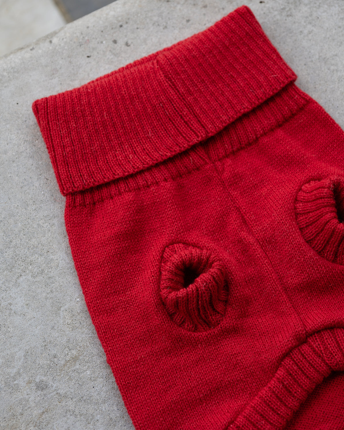 Underside of the cherry red wool jumper showing ribbed leg holes