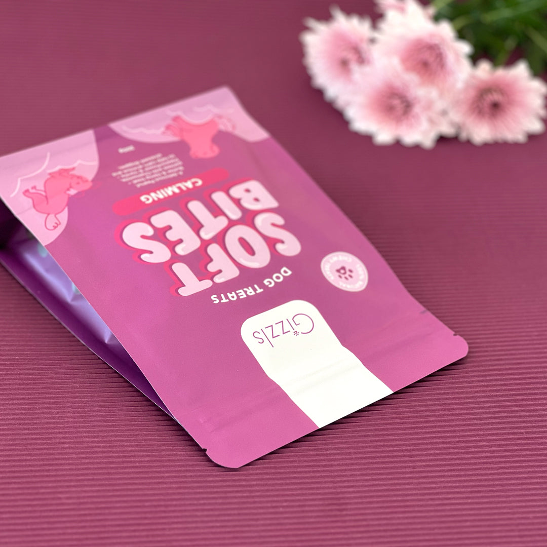 Gizzls Soft Bites Calming bag lying on a plum surface with pink chrysanthemums