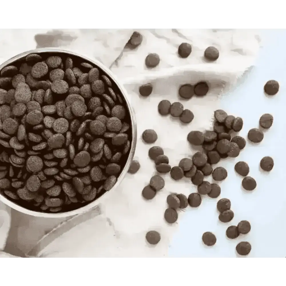 Bowl of round brown dry dog food kibble spilling onto a cream cloth