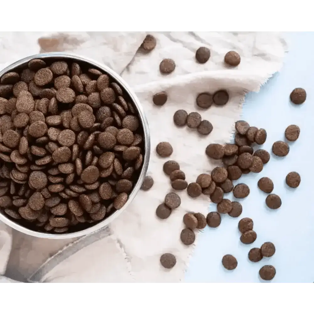 Bowl of brown dry dog kibble spilling onto a linen cloth