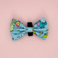 Jurassic Party Dog Bow Tie with colourful dinosaur print on light blue, pink background