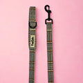 Foxbury Plaid Dog Lead laid flat on pink, showing the brown and cream check handle and black clip