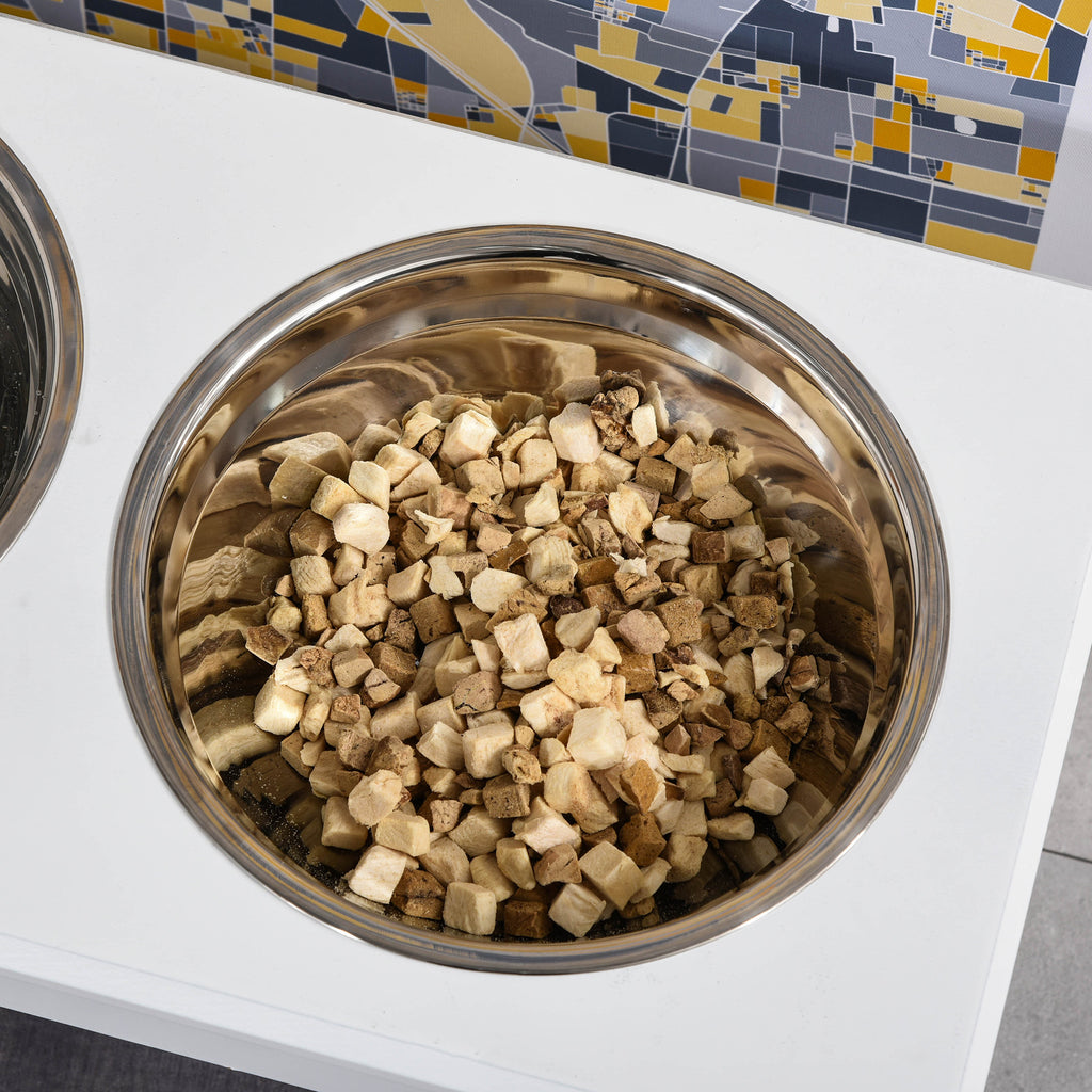 Stainless steel bowl filled with dry treats in the white feeding stand