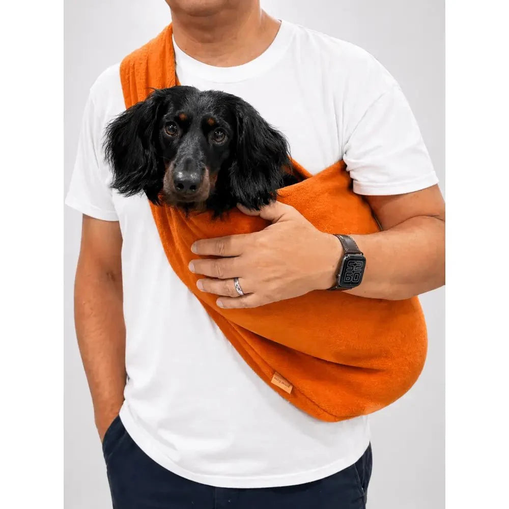 Man carrying a black spaniel-type dog in a rust orange Plain Fleece Dog Sling