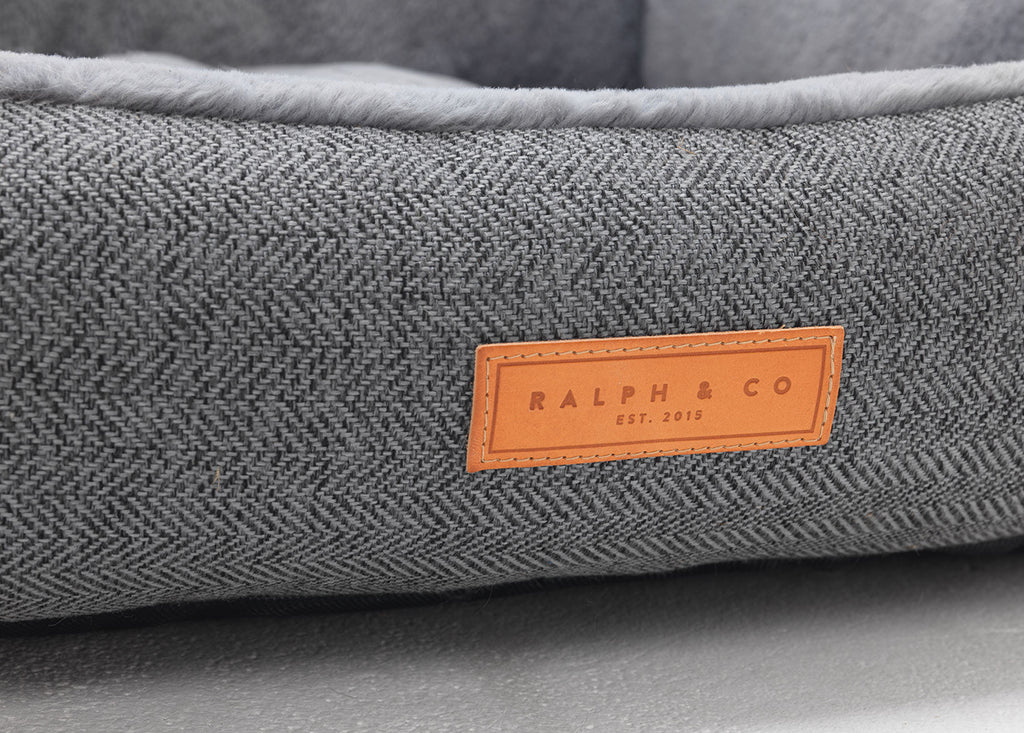Close-up of grey herringbone fabric and the leather Ralph & Co badge