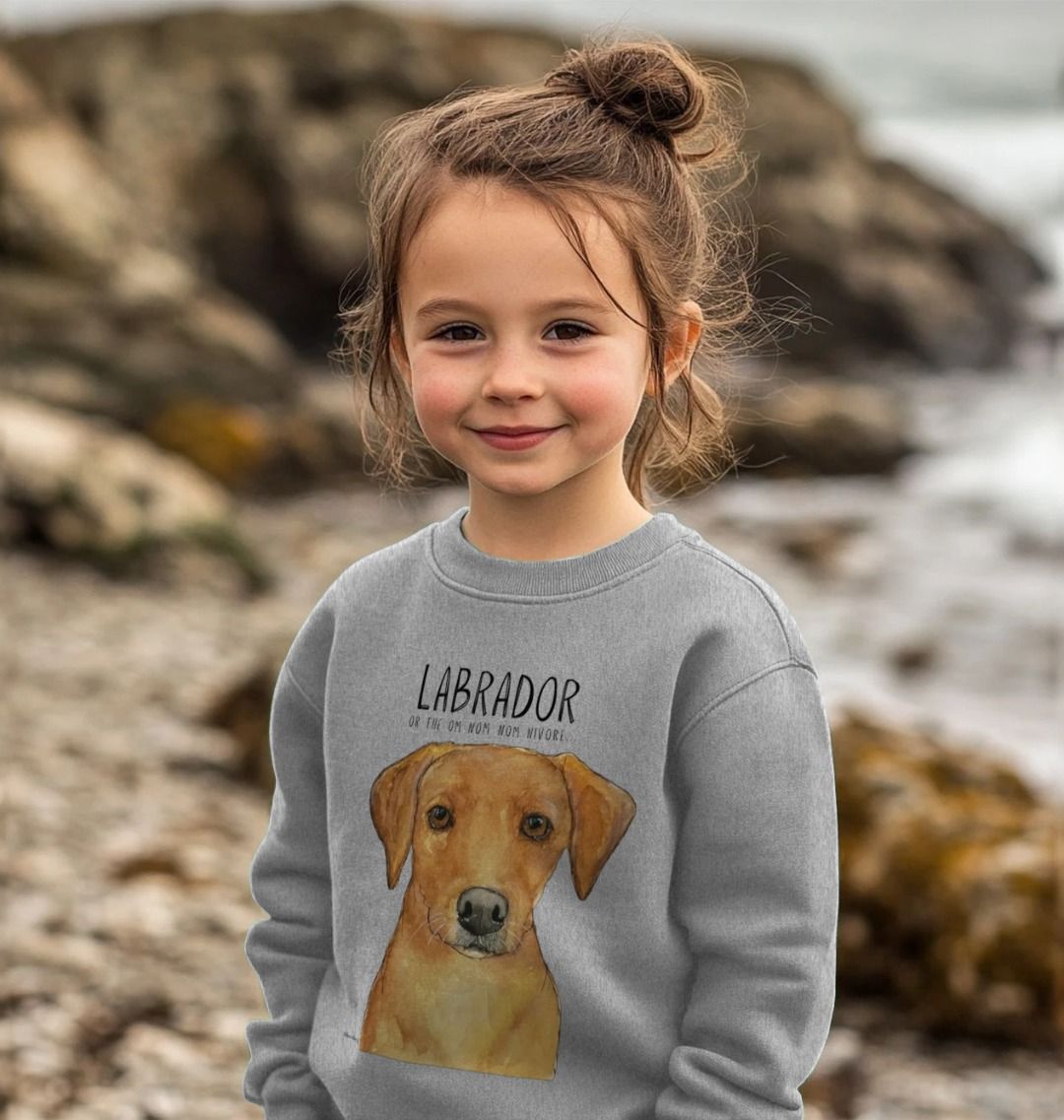 Smiling girl on a rocky beach wearing the grey kids' sweatshirt with a fox red Labrador print