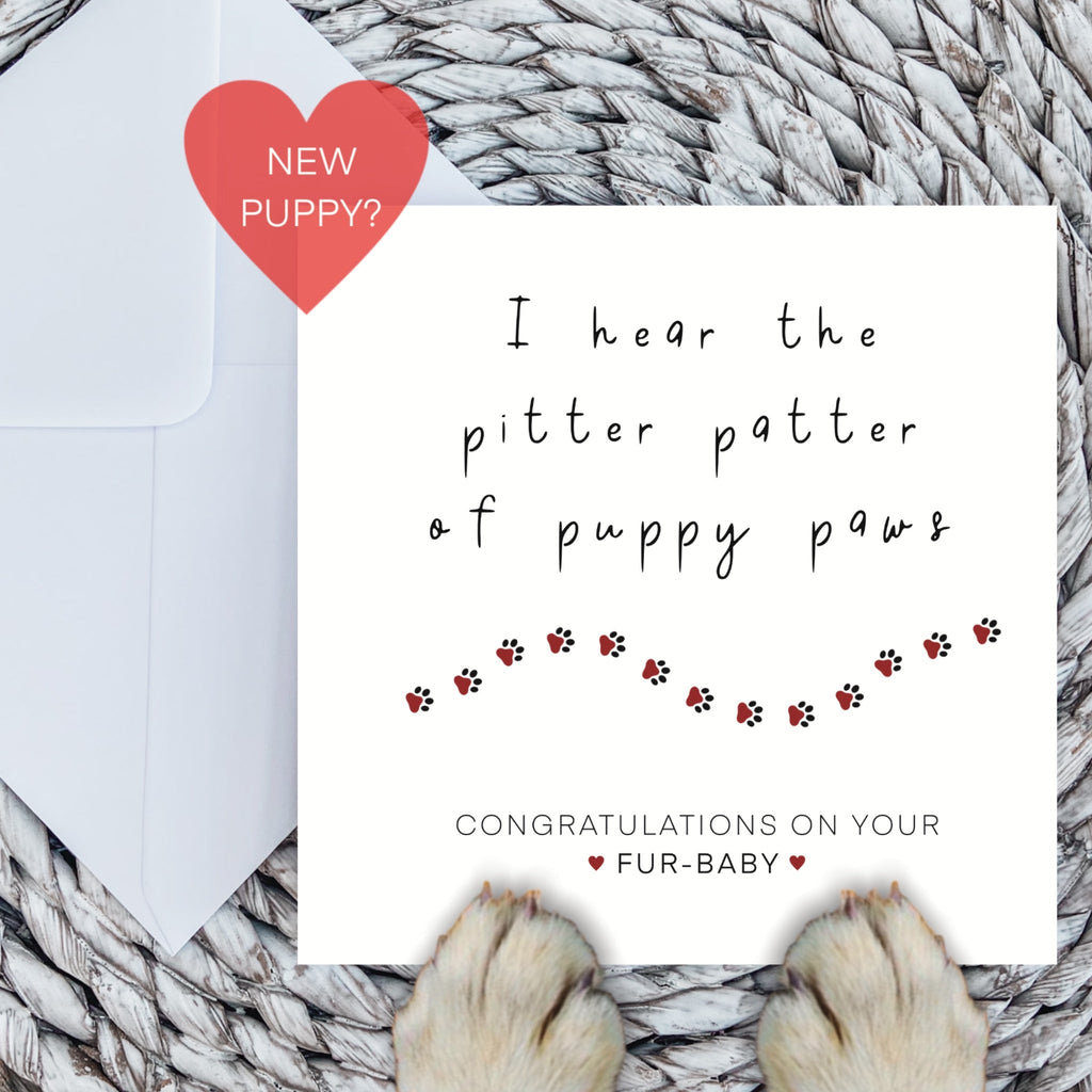 New puppy card with red paw print trail and dog paws on a woven mat