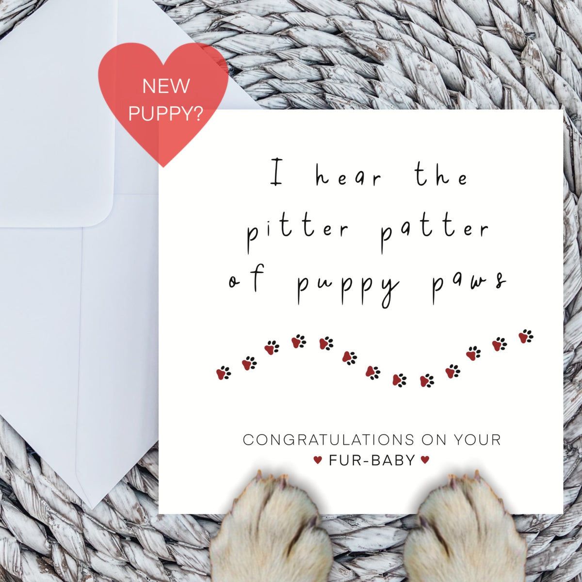New puppy card with red paw print trail and dog paws on a woven mat