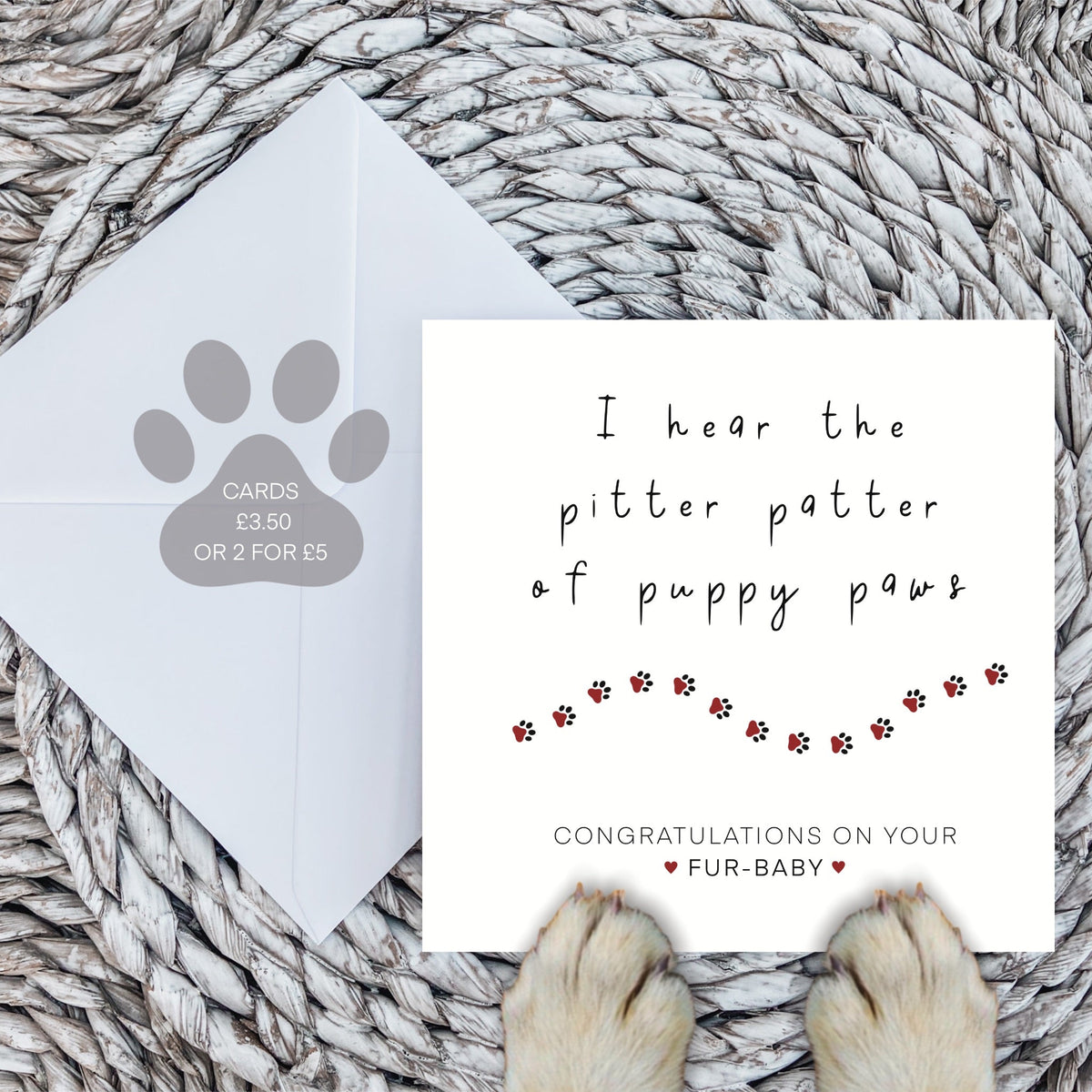New puppy card and white envelope on a woven mat with dog paws in front