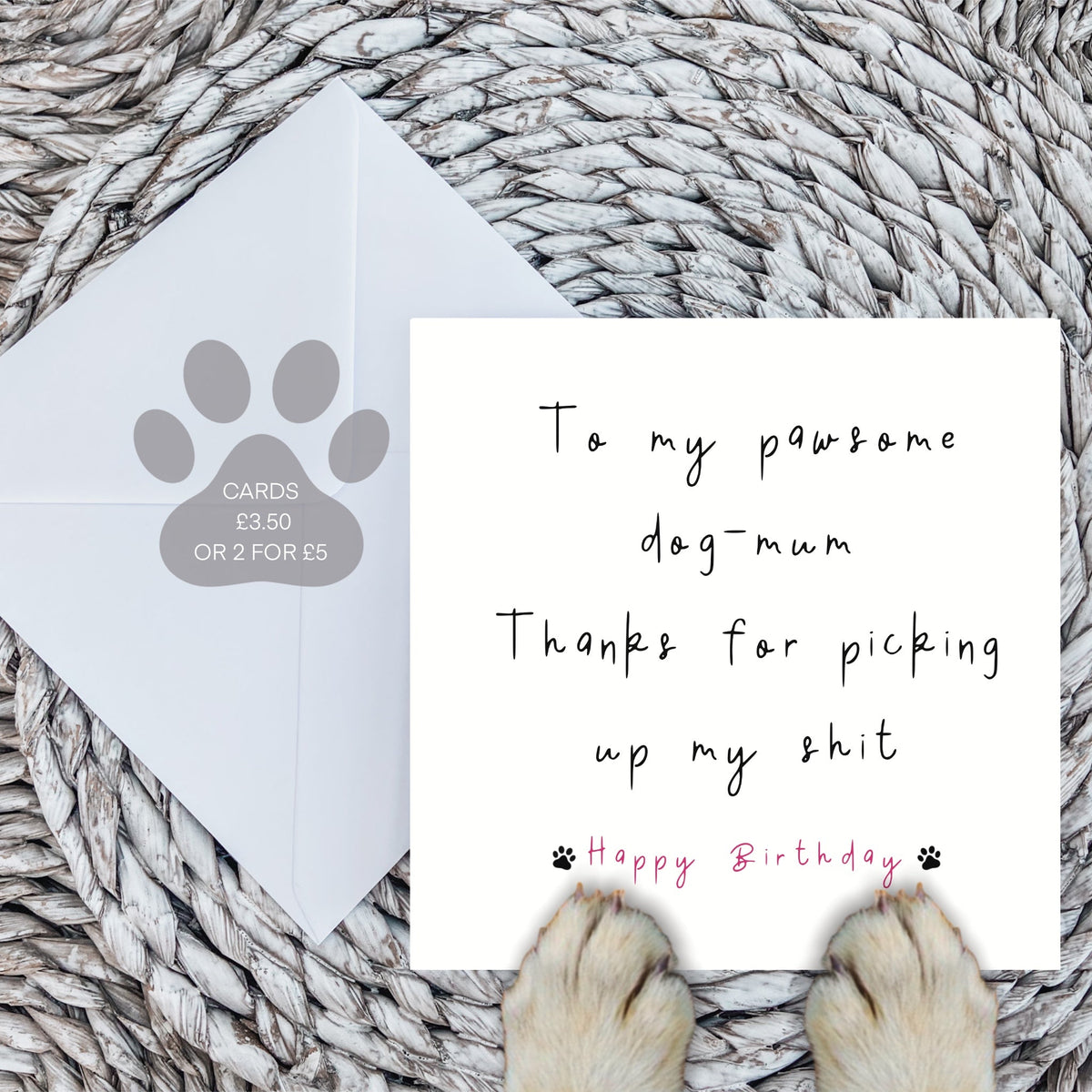 Dog mum birthday card and white envelope on a woven mat with dog paws in front