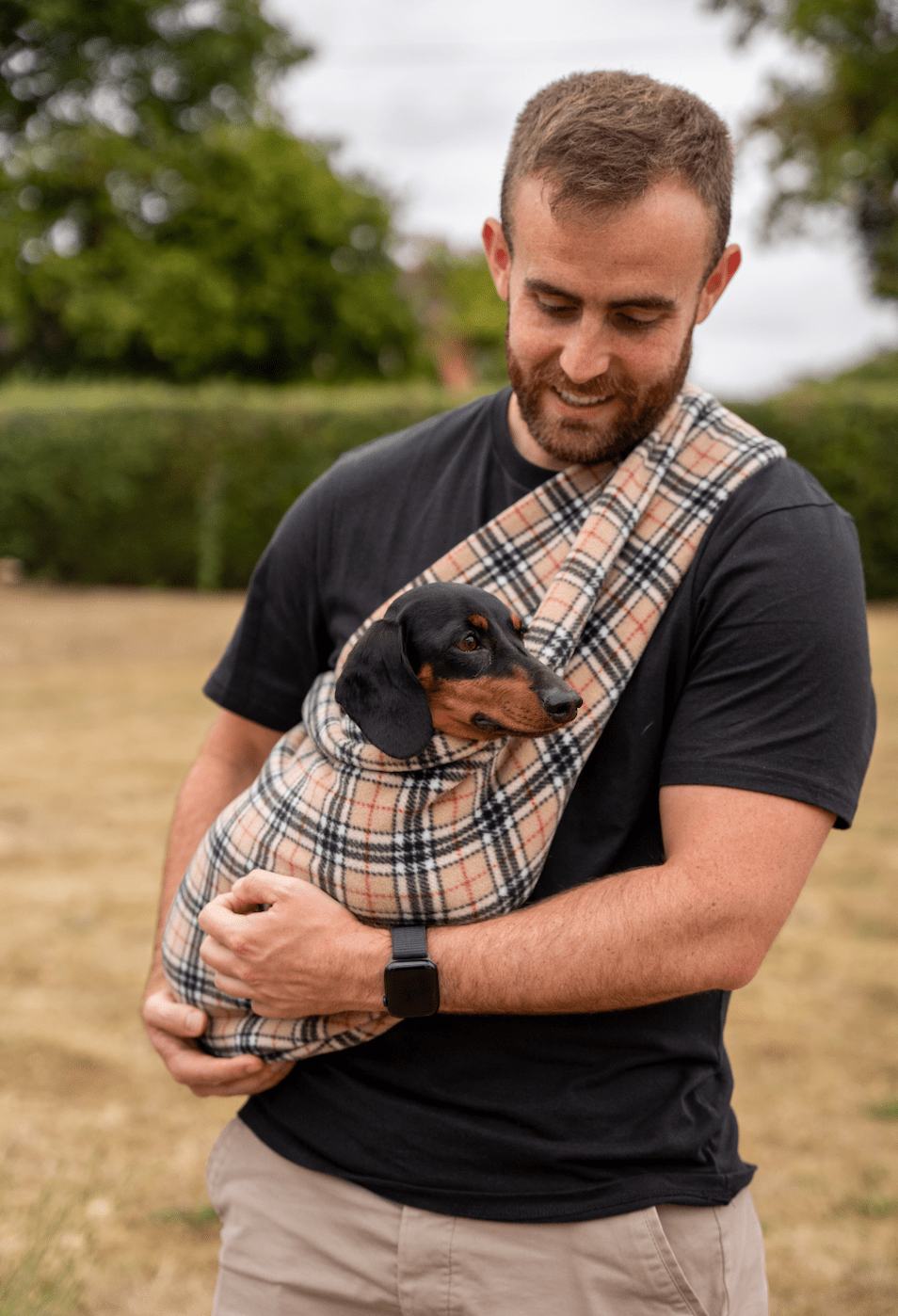 Man carrying a dachshund in a beige tartan Patterned Fleece Dog Sling, Long Strap size