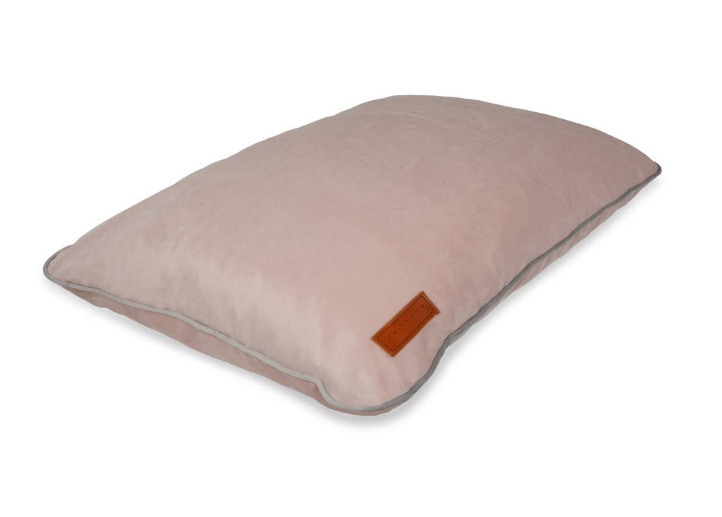 Pink memory foam dog crate mattress shown at an angle with leather Ralph & Co badge