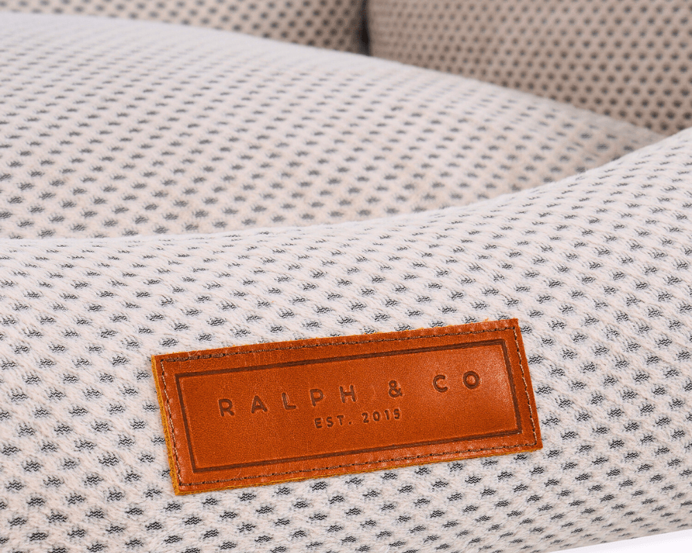 Close-up of the leather Ralph & Co badge on the beige knitted fabric