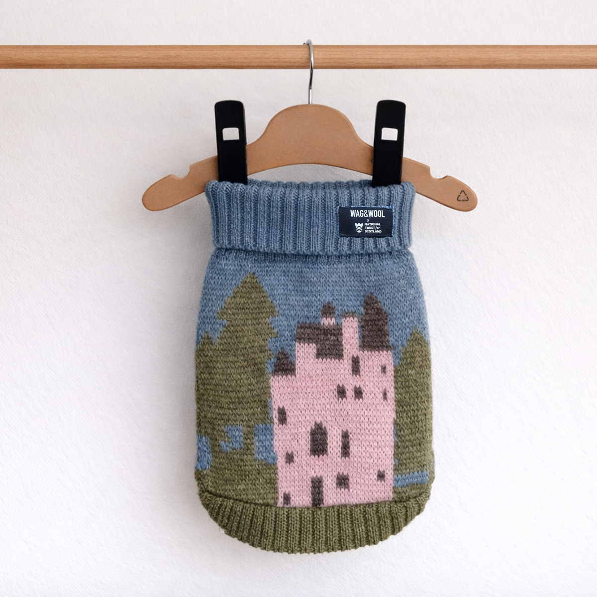 Pink castle wool dog jumper hanging on a wooden hanger