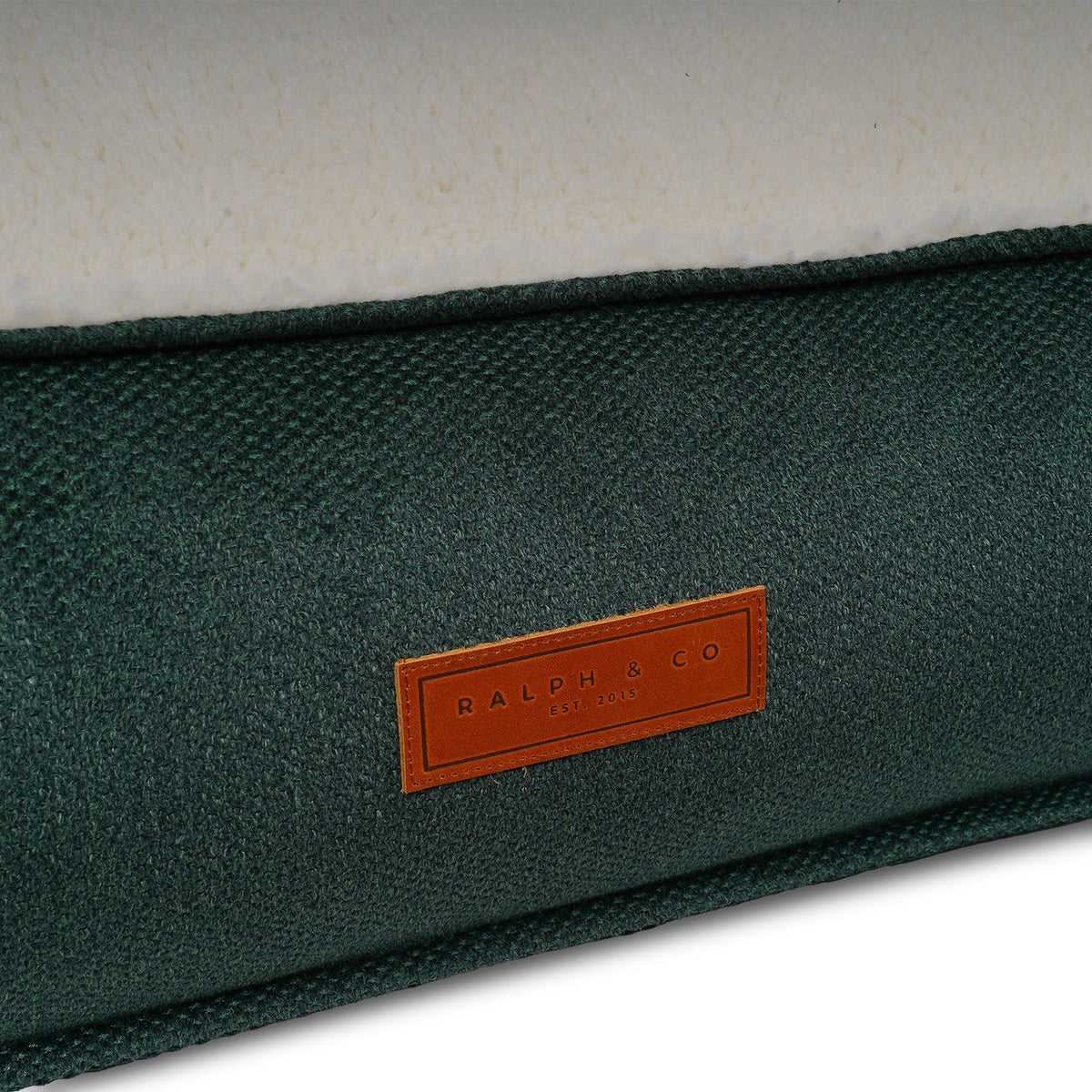 Close-up of the leather Ralph & Co badge on the green Richmond pillow bed