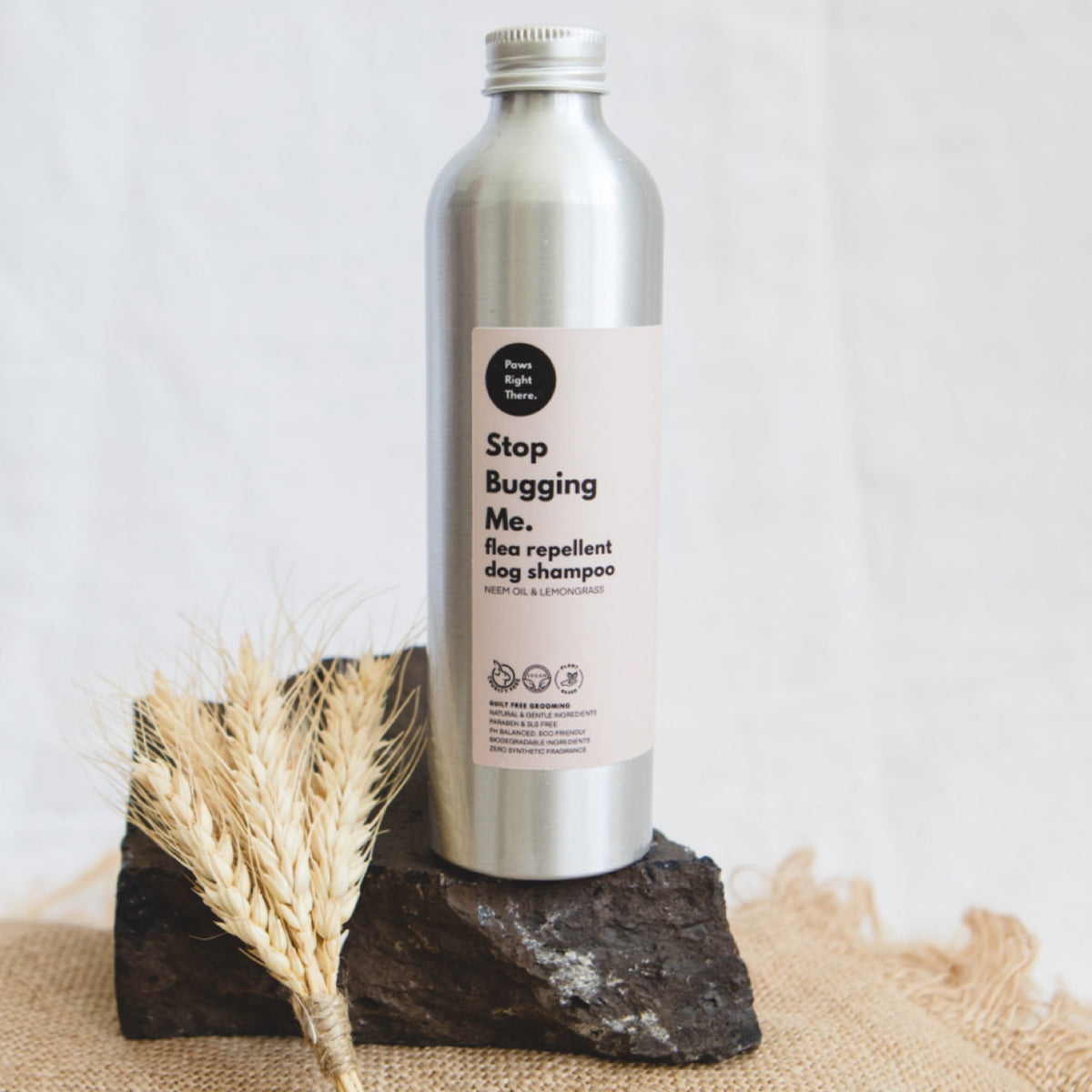 Neem and lemongrass dog shampoo bottle on a rock with dried wheat