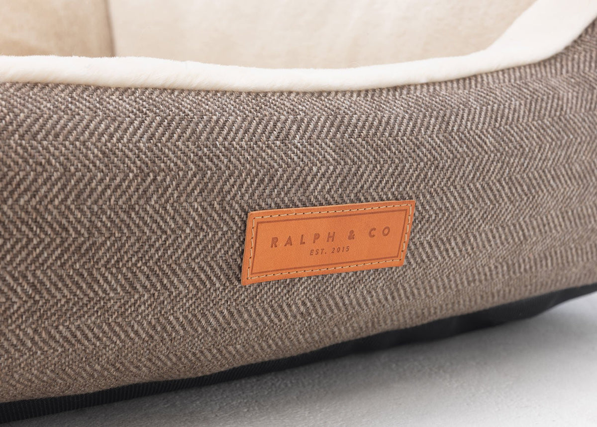 Close-up of brown herringbone tweed and the leather Ralph & Co badge