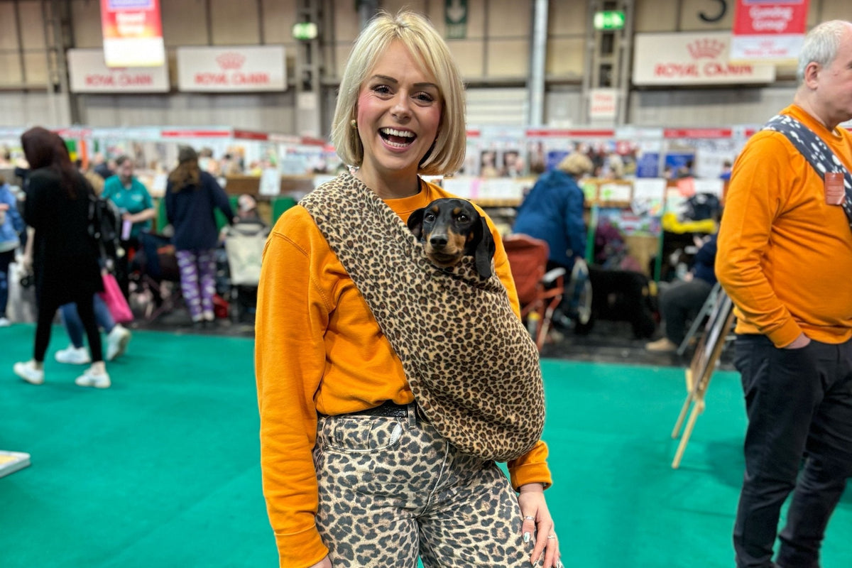 Woman at a dog show carrying a dachshund in a leopard Patterned Fleece Dog Sling